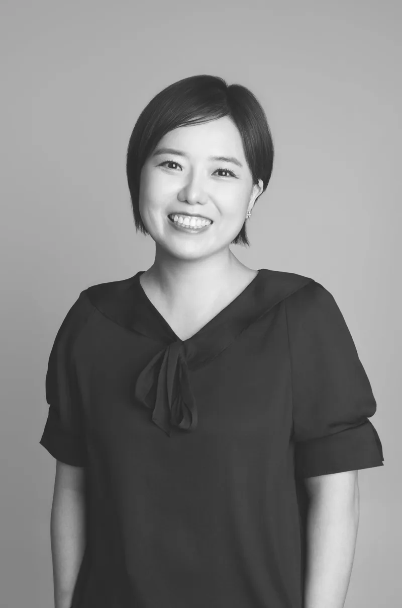 리본 블라우스를 입고 웃고 있는 정유진의 흑백 사진